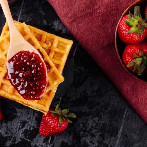 top-view-strawberry-jam-waffles-black-background